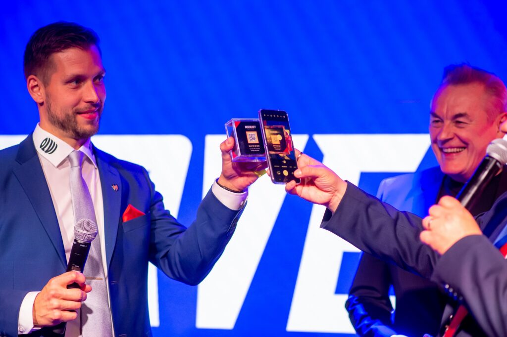 A man is holding a smart puck in a small case with a QR code. Another man is scanning the code with his phone.